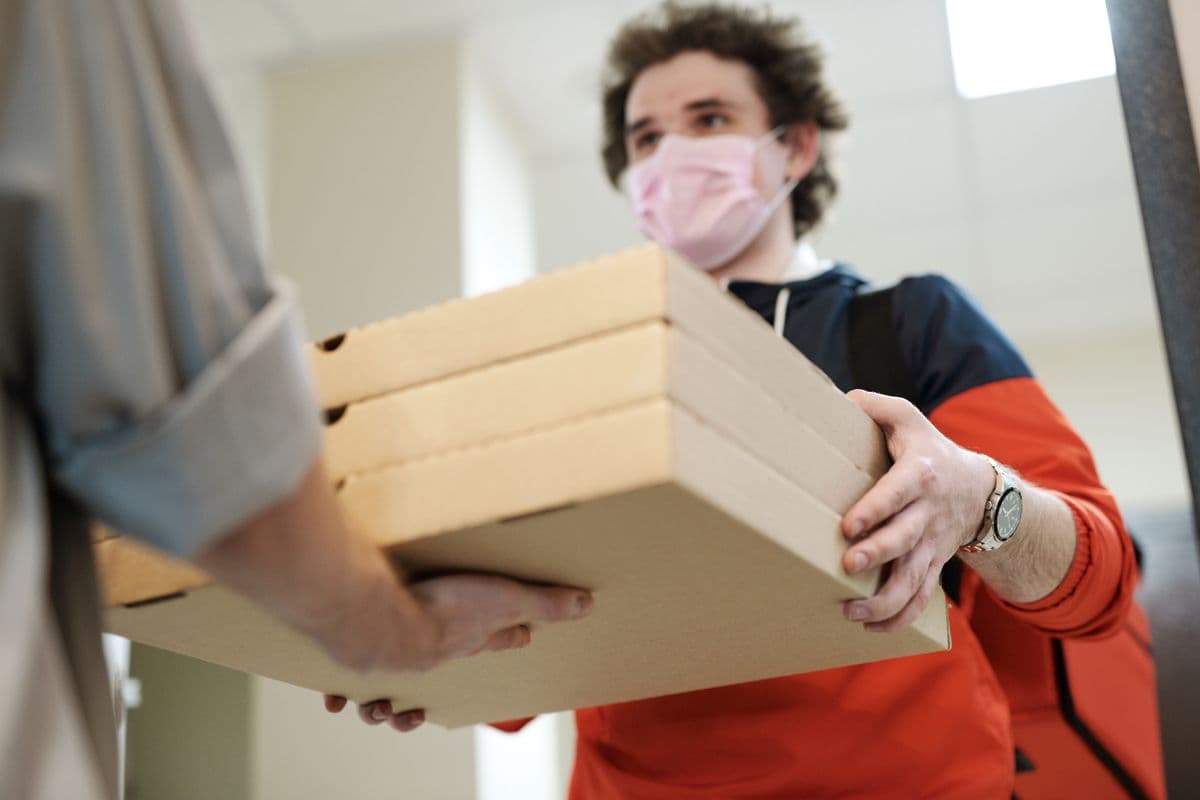Food delivery rider delivering pizza boxes to a customer at the door